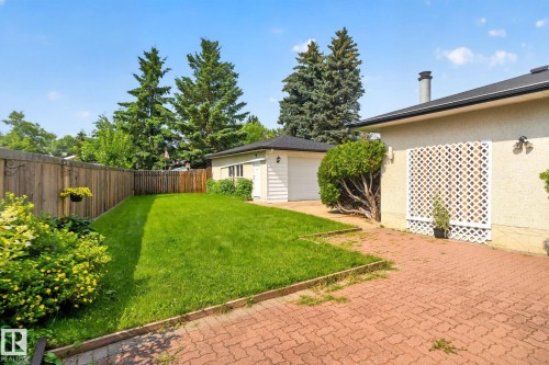 Expansive backyard featuring a manicured lawn, red paver patio, and mature perimeter trees - 6012 145 Avenue Nw, Edmonton, AB - Outdoor