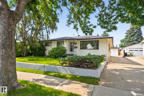 Ranch-style residence featuring light-colored siding, dark trim windows, and a black shingle roof - 6012 145 Avenue Nw, Edmonton, AB - Outdoor