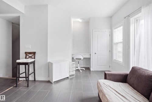 Spacious room featuring large format tile flooring, white walls, and a built-in desk area - #22 723 172 Street Sw, Edmonton, AB - Indoor