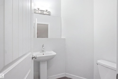 Pedestal sink with chrome faucet, large vanity mirror, and modern overhead lighting fixture - #22 723 172 Street Sw, Edmonton, AB - Indoor Photo Showing Bathroom