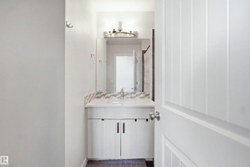 Bathroom vanity featuring a vessel sink, single-handle faucet, and mosaic tile backsplash - #22 723 172 Street Sw, Edmonton, AB - Indoor Photo Showing Bathroom