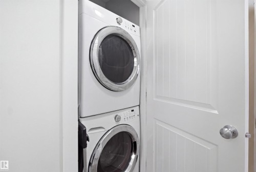 Integrated stackable washer and dryer appliances within a white paneled closet - #22 723 172 Street Sw, Edmonton, AB - Indoor Photo Showing Laundry Room