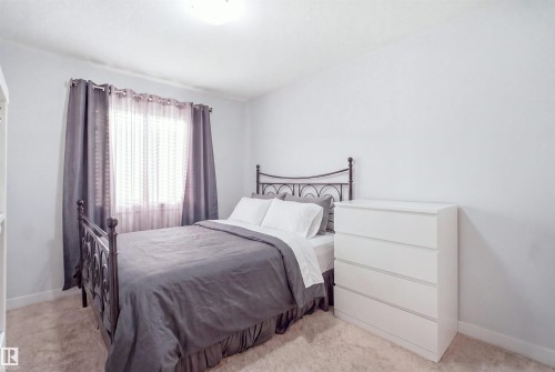 Bright bedroom featuring neutral wall paint, light-colored carpet flooring, and a window with sheer and blackout curtains - #22 723 172 Street Sw, Edmonton, AB - Indoor Photo Showing Bedroom