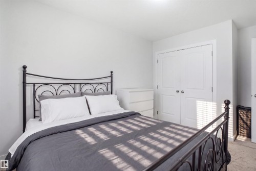 Neutral-toned room featuring a double-door closet with white paneled doors and polished chrome hardware - #22 723 172 Street Sw, Edmonton, AB - Indoor Photo Showing Bedroom