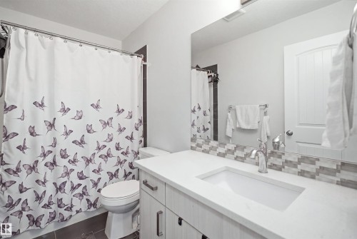 Bathroom featuring a light wood-finish vanity with a white countertop and integrated sink, chrome faucet, and a large mirror - #22 723 172 Street Sw, Edmonton, AB - Indoor Photo Showing Bathroom