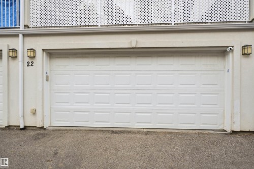 White panel-style garage door with exterior wall lanterns and a decorative lattice balcony railing - #22 723 172 Street Sw, Edmonton, AB - Outdoor With Exterior