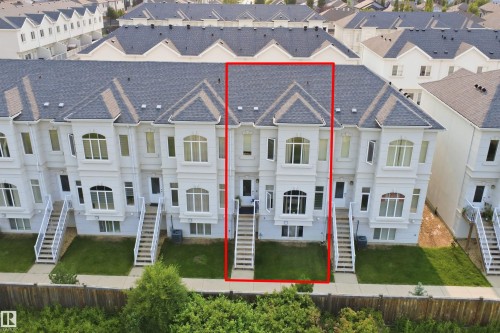 Townhouse exterior featuring a light-colored facade, multi-pane windows, and a dark shingle roof - #22 723 172 Street Sw, Edmonton, AB - Other