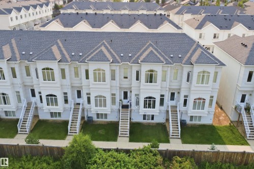 Contemporary townhome exterior featuring light-colored siding, dark shingle roofs, multiple bay windows, individual front entrances, and landscaped front yards - #22 723 172 Street Sw, Edmonton, AB - Other