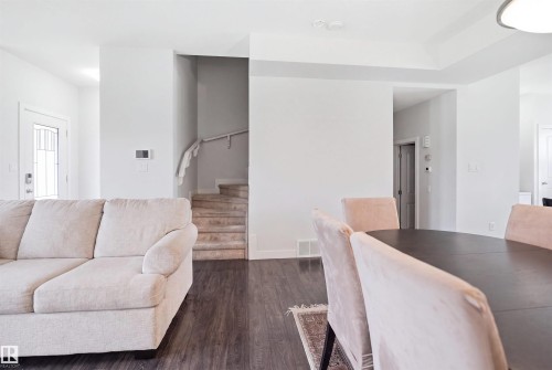 Open-concept living area featuring wood-finish flooring, white painted walls, and a staircase with a white painted handrail - #22 723 172 Street Sw, Edmonton, AB - Indoor Photo Showing Living Room