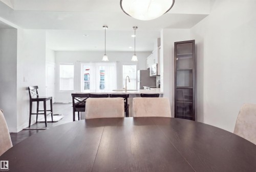 Spacious open-concept interior featuring light-toned walls, dark wood-finish flooring, and a kitchen with stainless steel appliances - #22 723 172 Street Sw, Edmonton, AB - Indoor Photo Showing Dining Room