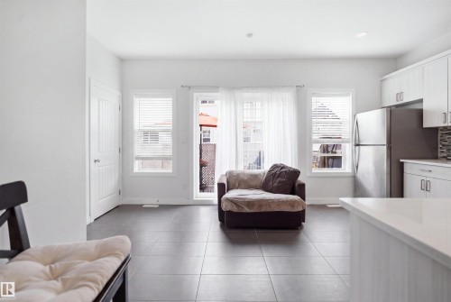 Open-concept living area featuring large format tile flooring, white walls, and multiple windows with blinds - #22 723 172 Street Sw, Edmonton, AB - Indoor