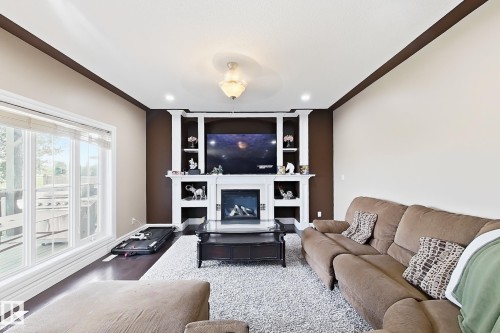 Living area featuring a prominent built-in media center with fireplace, recessed lighting, and a chandelier-style fixture - 5931 12 Avenue Sw, Edmonton, AB - Indoor Photo Showing Living Room With Fireplace