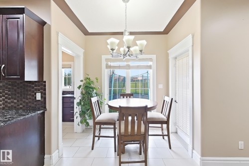 Dining area featuring light ceramic tile flooring, a multi-light chandelier, and an exterior door with louvered blinds - 5931 12 Avenue Sw, Edmonton, AB - Indoor Photo Showing Dining Room