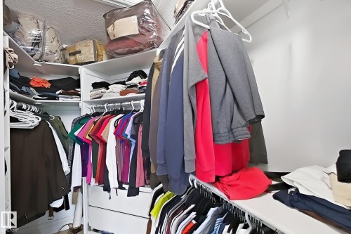 Walk-in closet featuring white built-in shelving, multiple hanging rods, and integrated drawer storage - 5931 12 Avenue Sw, Edmonton, AB - Indoor With Storage