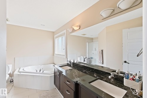 Dual sink vanity with dark cabinetry and a black stone countertop - 5931 12 Avenue Sw, Edmonton, AB - Indoor Photo Showing Bathroom