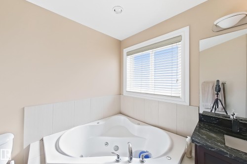 Corner soaking tub with tile surround, a window with blinds, and recessed ceiling lighting - 5931 12 Avenue Sw, Edmonton, AB - Indoor Photo Showing Bathroom