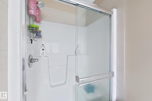 Shower enclosure featuring a sliding glass door and white surround - 5931 12 Avenue Sw, Edmonton, AB - Indoor Photo Showing Bathroom