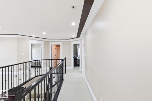Spacious upper-level landing featuring a wrought iron railing, recessed lighting, crown molding, and neutral-toned carpeting - 5931 12 Avenue Sw, Edmonton, AB - Indoor Photo Showing Other Room