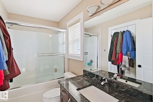 Bathroom featuring a dark wood-finish vanity with a black stone countertop and undermount sink - 5931 12 Avenue Sw, Edmonton, AB - Indoor Photo Showing Bathroom