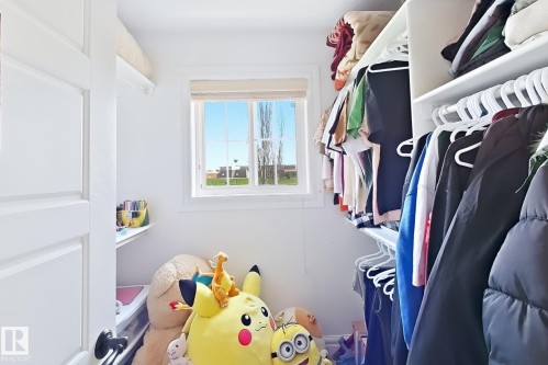 Walk-in closet with window, white built-in shelving, and hanging rods - 5931 12 Avenue Sw, Edmonton, AB - Indoor With Storage