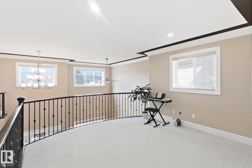 Carpeted loft area featuring a curved wrought iron railing, two large windows, recessed lighting, and crown molding - 5931 12 Avenue Sw, Edmonton, AB - Indoor Photo Showing Other Room
