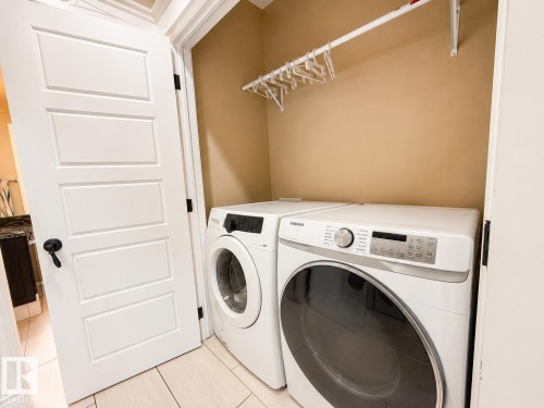 Dedicated laundry area with a white front-load washer and dryer set - 5931 12 Avenue Sw, Edmonton, AB - Indoor Photo Showing Laundry Room