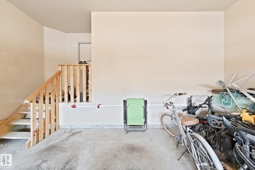 Interior staircase with natural wood railing and balusters, featuring a concrete floor and neutral wall finishes - 5931 12 Avenue Sw, Edmonton, AB - Indoor Photo Showing Other Room