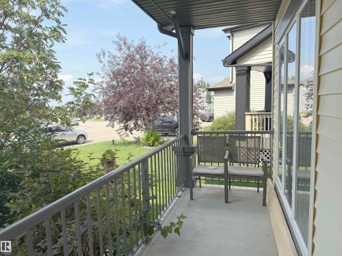 Covered front porch featuring a concrete surface, dark grey railing, and light-colored siding - 5931 12 Avenue Sw, Edmonton, AB - Outdoor With Exterior