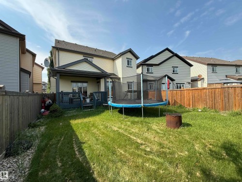Expansive green lawn with wooden fencing, featuring a covered rear deck with dark wood railing, and light-colored siding on the exterior - 5931 12 Avenue Sw, Edmonton, AB - Outdoor With Deck Patio Veranda With Backyard With Exterior