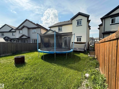 Expansive green backyard featuring a privacy fence, fire pit, and a sliding glass door leading to the interior - 5931 12 Avenue Sw, Edmonton, AB - Outdoor With Exterior