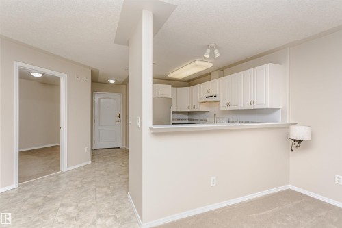 Kitchen featuring white cabinetry, stainless steel appliances, and a breakfast bar - #413 237 Youville Dr E Nw, Edmonton, AB - Indoor