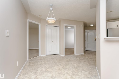 Entryway featuring tile-finish flooring, a contemporary pendant light fixture, and neutral wall tones - #413 237 Youville Dr E Nw, Edmonton, AB - Indoor Photo Showing Other Room