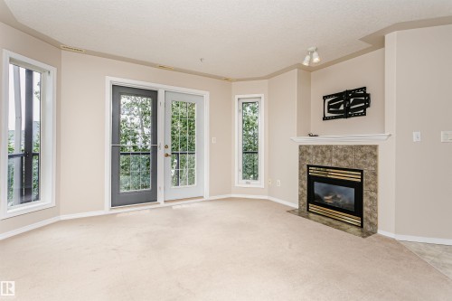 Living area featuring a gas fireplace with a tiled surround and mantelpiece - #413 237 Youville Dr E Nw, Edmonton, AB - Indoor Photo Showing Living Room With Fireplace