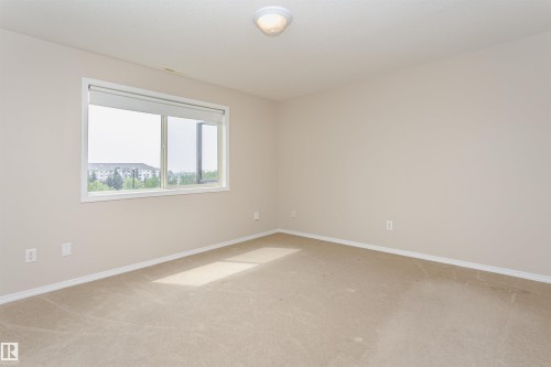 Room featuring neutral wall paint, light-colored carpeting, a large window, and white trim - #413 237 Youville Dr E Nw, Edmonton, AB - Indoor Photo Showing Other Room