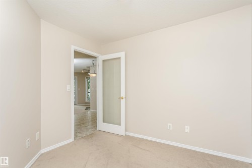 Interior room with neutral wall paint and carpeting, featuring a white door with frosted glass paneling - #413 237 Youville Dr E Nw, Edmonton, AB - Indoor Photo Showing Other Room