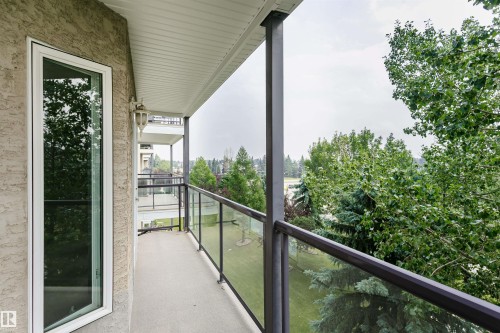 Outdoor balcony featuring a textured stucco exterior, white window trim, and a built-in wall sconce - #413 237 Youville Dr E Nw, Edmonton, AB - Outdoor With Balcony With Exterior