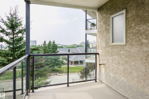 Private balcony featuring glass railings, a textured exterior wall, and a frosted window - #413 237 Youville Dr E Nw, Edmonton, AB - Outdoor With Balcony With Exterior
