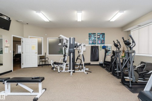 Dedicated fitness room featuring a multi-station weight machine, multiple elliptical trainers, and cardio equipment - #413 237 Youville Dr E Nw, Edmonton, AB - Indoor Photo Showing Gym Room