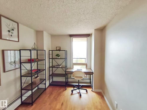 Hardwood-finish flooring highlights this versatile room, featuring a large window with natural light, baseboard heating, and smooth wall finishes - #509 10149 Saskatchewan Dr Nw, Edmonton, AB - Indoor Photo Showing Office