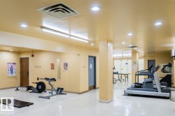 Fitness area featuring bright recessed lighting, light-colored flooring, and a variety of exercise equipment - 