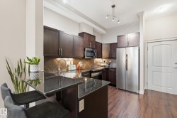 Kitchen with dark wood-finish cabinetry, black granite countertops, diagonal tile backsplash, and stainless steel appliances - 