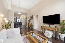 Living area featuring wood-finish flooring, vaulted ceilings, and crown molding - 