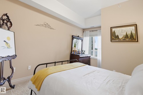 Carpeted room featuring a window with natural light, neutral wall colors, and white trim - #443 10121 80 Av Nw, Edmonton, AB - Indoor Photo Showing Bedroom