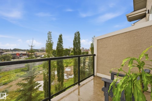 Outdoor balcony featuring a glass and metal railing, stucco exterior wall, and concrete flooring - #443 10121 80 Av Nw, Edmonton, AB - Outdoor With Balcony With Exterior