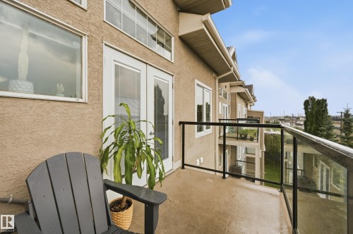 Outdoor balcony featuring a concrete floor, black metal and glass railing, and stucco exterior - #443 10121 80 Av Nw, Edmonton, AB - Outdoor With Balcony With Exterior