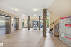 Building lobby featuring two stainless steel elevators, stacked stone columns, and wood-finish flooring - 