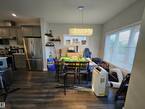 Open-concept living area featuring wood-finish flooring, a contemporary chandelier, and large windows - 13309 104 Street Nw, Edmonton, AB - Indoor