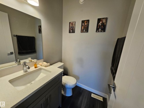 Bathroom featuring a grey vanity with a white countertop, an integrated sink with chrome faucet, a rectangular mirror, and dark wood-finish flooring - 13309 104 Street Nw, Edmonton, AB - Indoor Photo Showing Bathroom