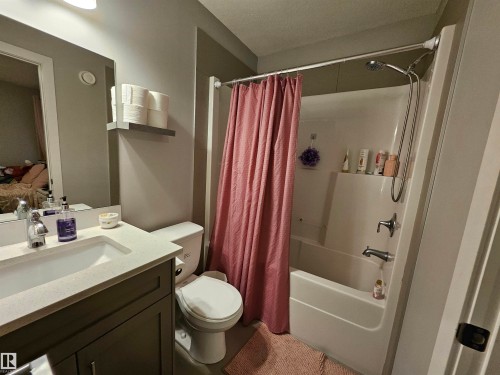 Bathroom featuring a vanity with a light-colored countertop and integrated sink, a white toilet, and a white tub with an overhead shower fixture - 13309 104 Street Nw, Edmonton, AB - Indoor Photo Showing Bathroom