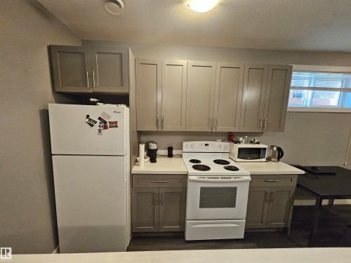 Kitchen featuring contemporary gray cabinetry, white countertops, built-in range, and a full-size refrigerator - 13309 104 Street Nw, Edmonton, AB - Indoor Photo Showing Kitchen